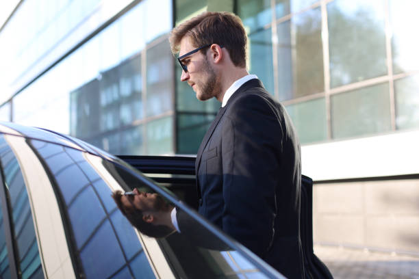 Elegant young businessman entering his car while standing outdoors